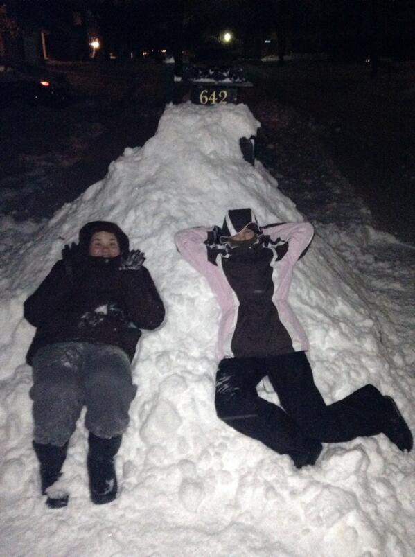 Two students lay in piles of shoveled snow