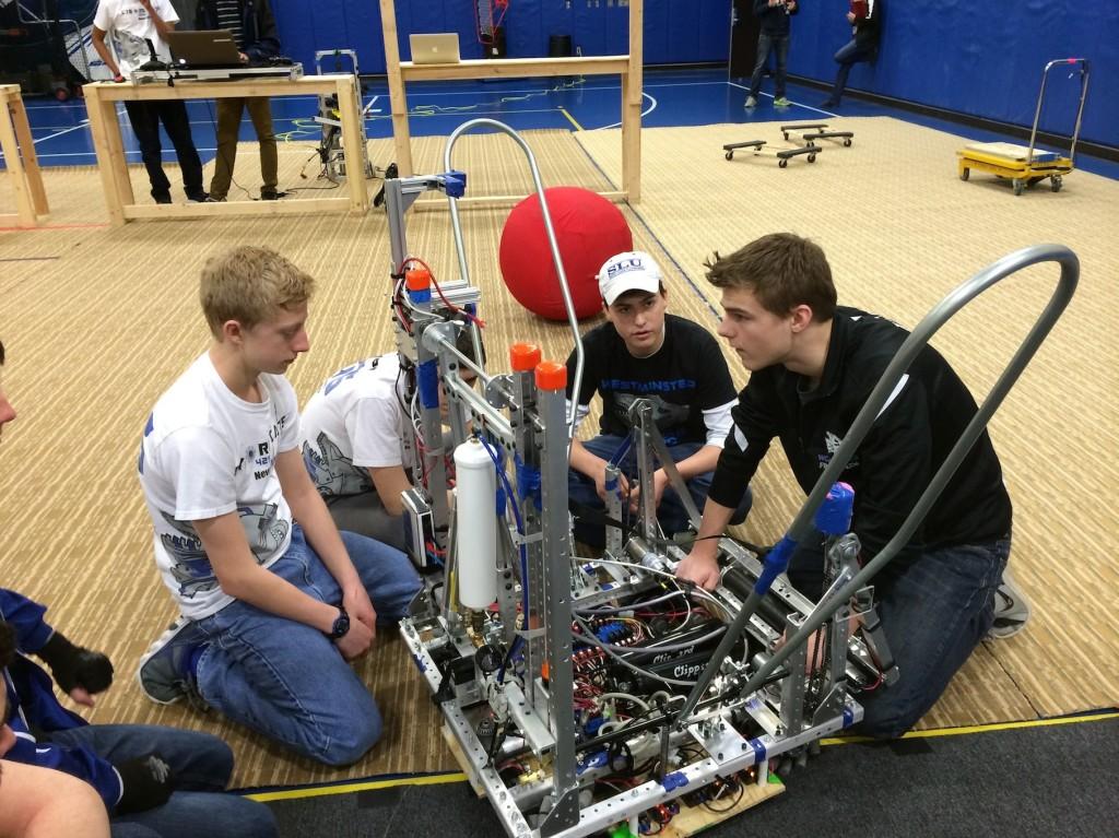 Matthew Hoekzema, freshman, Brennan Murphy, sophomore, and Alex Kessel, junior, work on this year's robot.