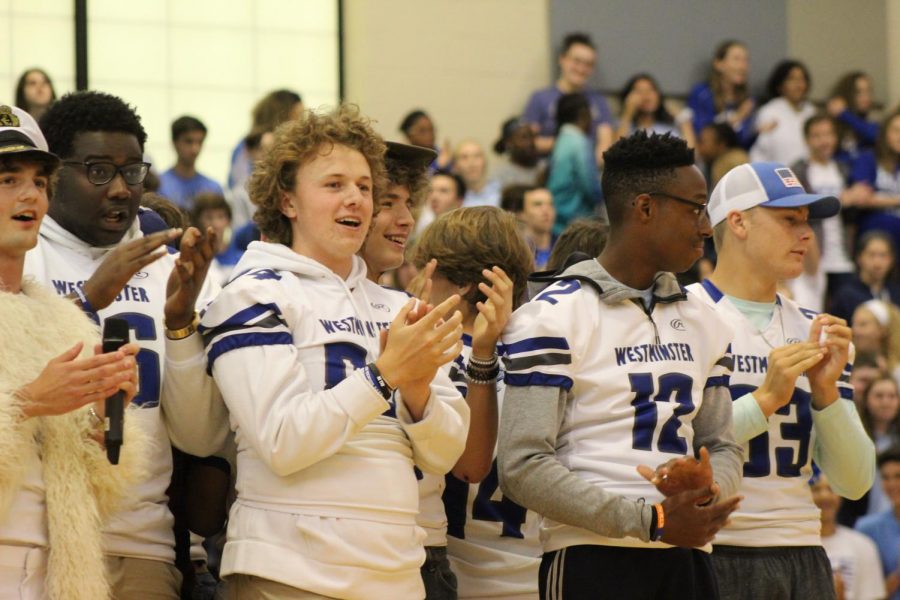 Varsity football players and cheerleaders perform a dance together at the Homecoming pep assembly. 