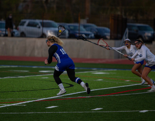 Kharis Perona runs down the field with the ball in her stick.