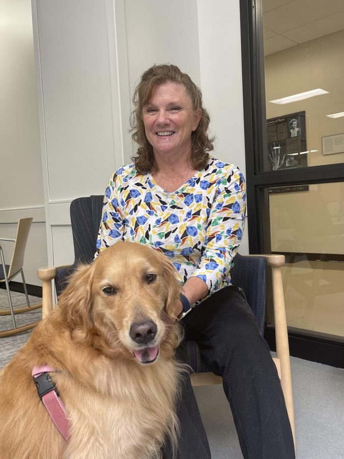 Mrs. Brown sits in the Hub while petting Millie. She enjoys having Millie back for the students. 