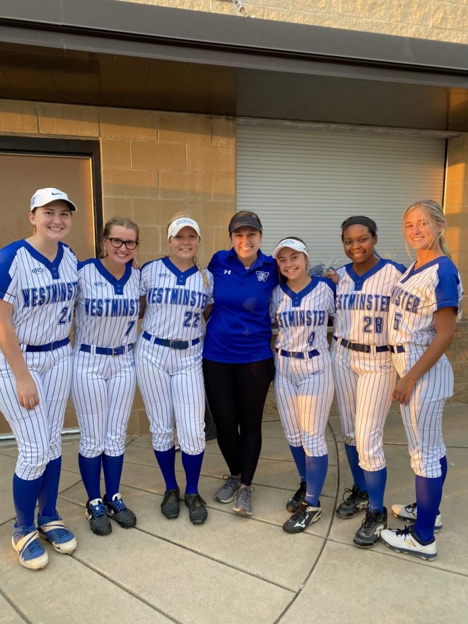 Coach Farmer smiles with the senior softball players on senior night.