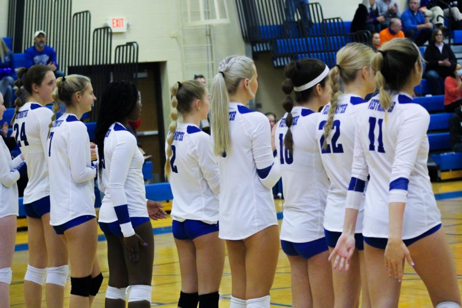 The girls volleyball team faces the net for the starting lineup in the district championship game.