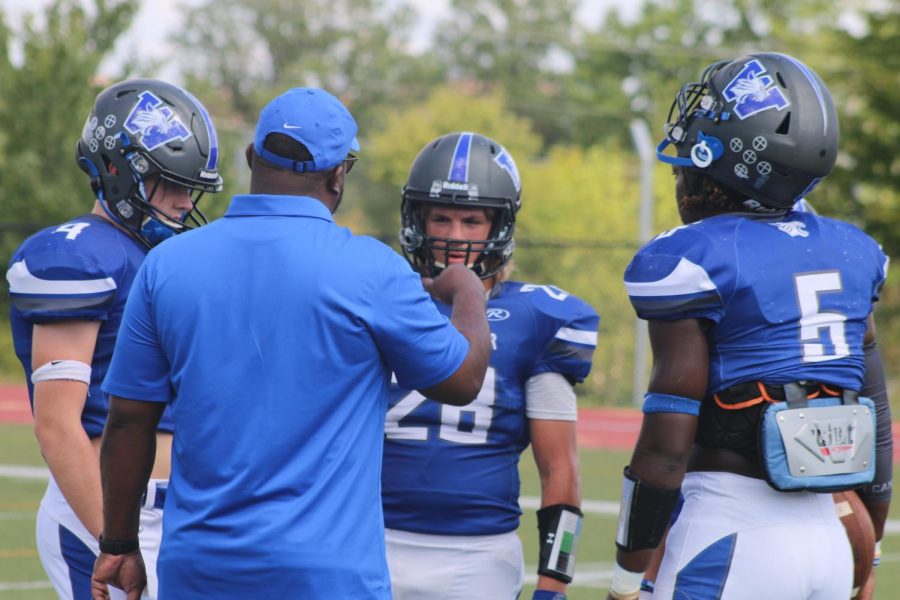 The football team listen to their coach for instructions.