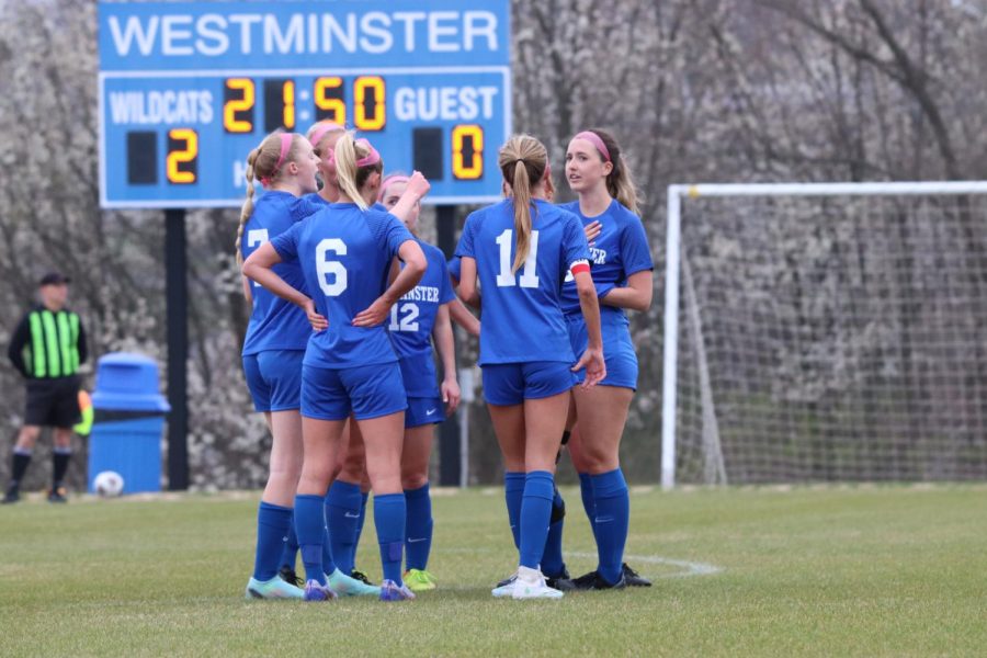 Girls soccer teams huddles before the ball is back in play.