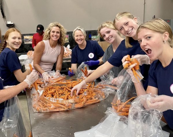 A group of girls gather as they serve in a kitchen.