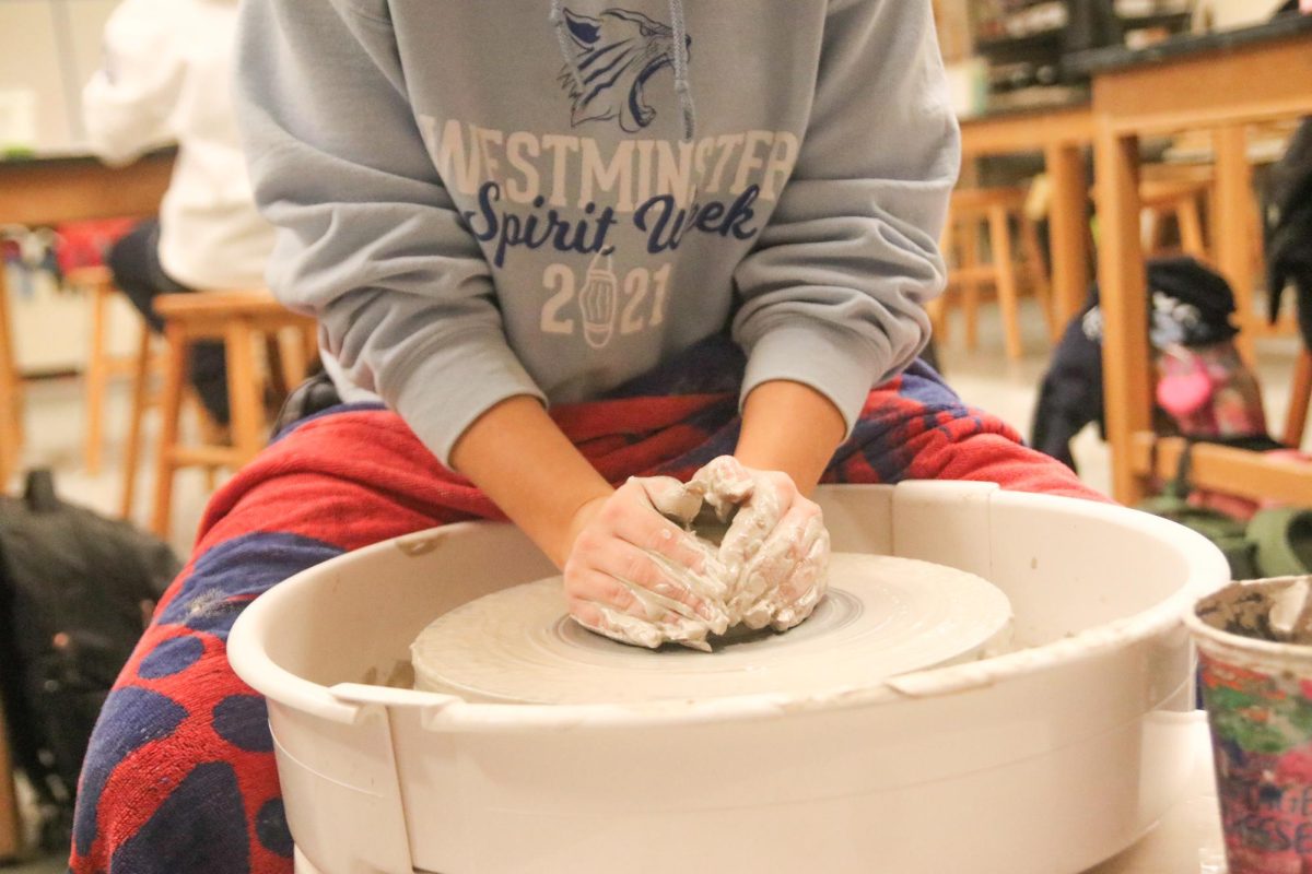 A student shapes a piece of clay on the ceramics wheel.