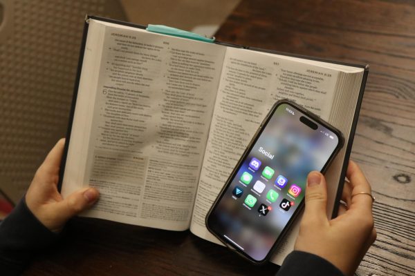 Image of a bible with a phone on top open to social media apps