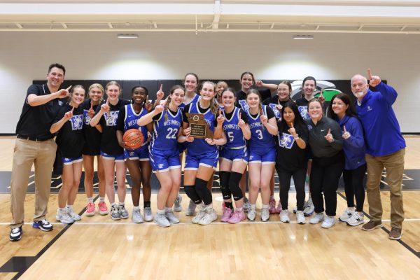 Girls Basketball team holding the district championship trophy 