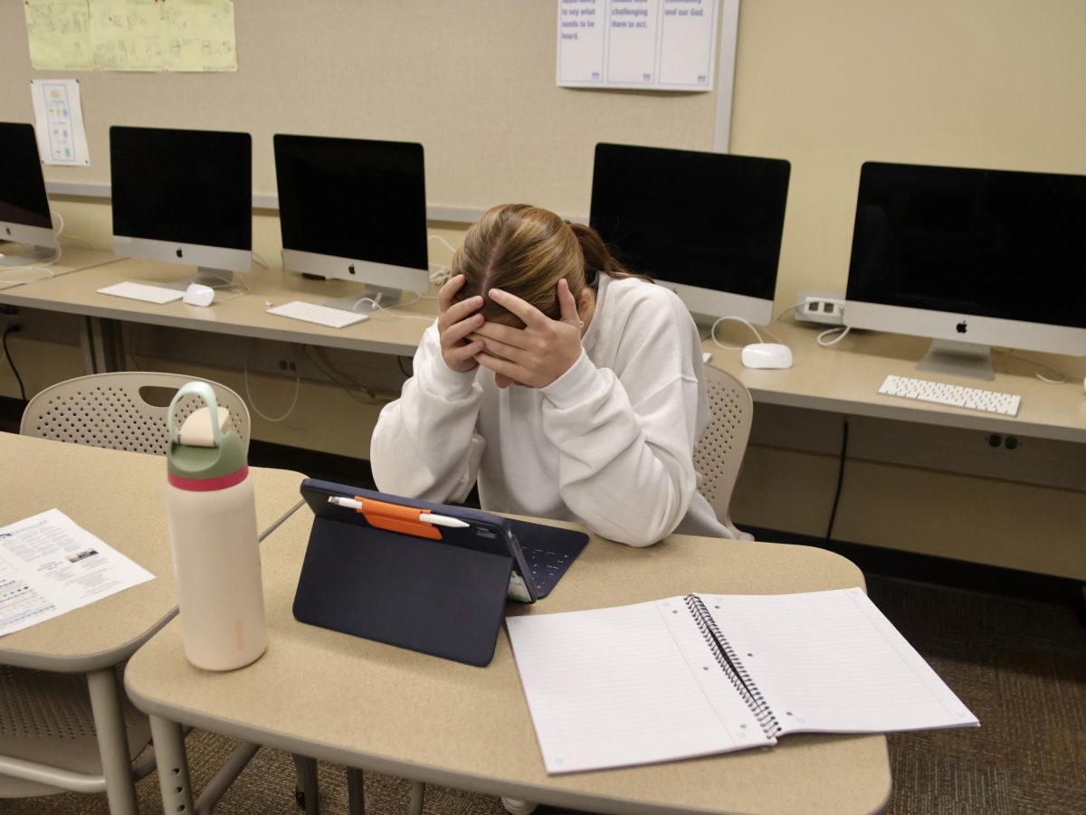 Senior student sits with head in her hands as she struggles with the early signs of senioritis.