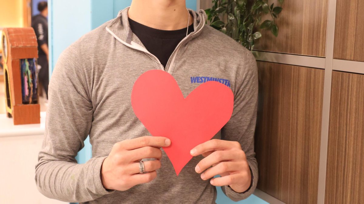 Westminster student holds a red paper heart, symbolizing the importance of empathy